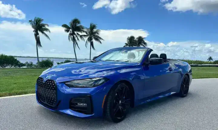 2022 BMW 430i convertible rental vehicle in blue, top down, Southwest Florida coastline