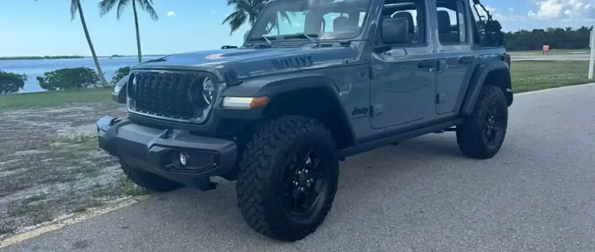 A 2025 Jeep Wrangler from the SWFL Auto Rentals fleet on a palm-lined road in Southwest Florida